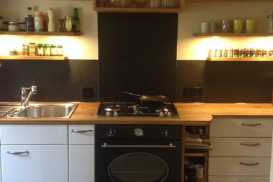 Ejemplo de cocina comedor lineal de estilo de casa de campo con fregadero integrado, armarios con paneles lisos, encimera de madera y suelo de baldosas de cerámica