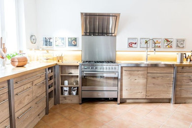 Immagine di una cucina country chiusa con top in legno, elettrodomestici in acciaio inossidabile e pavimento in terracotta