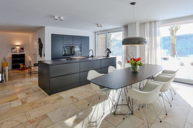 Moderne Küche mit integriertem Waschbecken, flächenbündigen Schrankfronten, schwarzen Schränken, schwarzen Elektrogeräten, Marmorboden, Kücheninsel, beigem Boden, schwarzer Arbeitsplatte und Tapetendecke in Köln