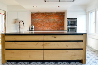 Photo of a large contemporary galley open plan kitchen in Dortmund with an integrated sink, flat-panel cabinets, dark wood cabinets, composite countertops, red splashback, stone slab splashback, stainless steel appliances, porcelain flooring, an island, multi-coloured floors and black worktops.