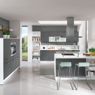 Large contemporary u-shaped open plan kitchen in Hamburg with an integrated sink, flat-panel cabinets, beige cabinets, wood benchtops, beige splashback, glass sheet splashback, stainless steel appliances, cement tiles, a peninsula and grey floor.