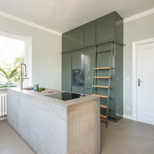 Zweizeilige, Mittelgroße Moderne Küche mit flächenbündigen Schrankfronten, grünen Schränken, grauer Arbeitsplatte, Unterbauwaschbecken, Elektrogeräten mit Frontblende, Halbinsel und grauem Boden in Berlin