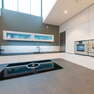 Aménagement d'une très grand cuisine moderne avec un plan de travail gris et des portes de placard blanches.
