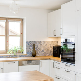 Mittelgroße Moderne Küche in L-Form mit Unterbauwaschbecken, Schrankfronten mit vertiefter Füllung, weißen Schränken, Arbeitsplatte aus Holz, bunter Rückwand, Elektrogeräten mit Frontblende, Kücheninsel und beiger Arbeitsplatte in München