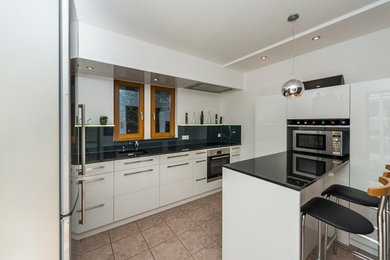 Small contemporary u-shaped open plan kitchen in Other with an integrated sink, white cabinets, stainless steel appliances, ceramic flooring and an island.