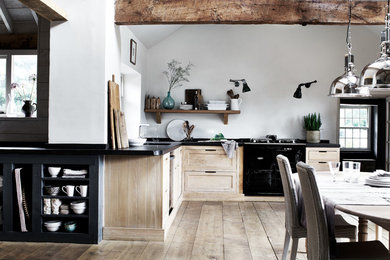 Foto på ett stort lantligt kök, med en rustik diskho, skåp i shakerstil, skåp i ljust trä, vitt stänkskydd, svarta vitvaror och ljust trägolv