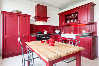 Landhausstil Küche mit Landhausspüle, Küchenrückwand in Rot und schwarzen Elektrogeräten in Sonstige