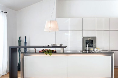 Offene, Einzeilige, Mittelgroße Moderne Küche mit integriertem Waschbecken, flächenbündigen Schrankfronten, weißen Schränken, Küchengeräten aus Edelstahl, hellem Holzboden und Kücheninsel in München