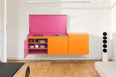 Einzeilige, Kleine Moderne Wohnküche ohne Insel mit Einbauwaschbecken, orangefarbenen Schränken und Küchenrückwand in Weiß in Düsseldorf