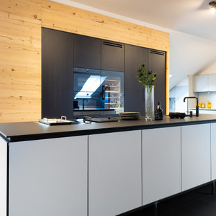 Mittelgroße Moderne Küche mit Unterbauwaschbecken, flächenbündigen Schrankfronten, schwarzen Schränken, schwarzen Elektrogeräten, Kücheninsel, schwarzem Boden und schwarzer Arbeitsplatte in München
