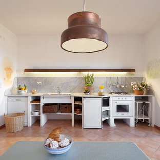 Foto di una grande cucina mediterranea con nessun'anta, ante bianche, paraspruzzi grigio, elettrodomestici bianchi, pavimento in terracotta, nessuna isola e pavimento arancione