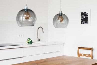 Expansive scandinavian single-wall kitchen/diner in Berlin with flat-panel cabinets, white cabinets, wood worktops, white splashback, no island and white worktops.