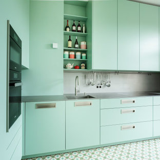 Idee per una piccola cucina a L contemporanea chiusa con lavello integrato, ante lisce, ante turchesi, top in acciaio inossidabile, paraspruzzi grigio, paraspruzzi con piastrelle di metallo, elettrodomestici neri, pavimento turchese e top grigio