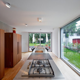 Design ideas for a large contemporary eat-in kitchen in Frankfurt with an integrated sink, with island, stainless steel benchtops, grey splashback, medium hardwood floors, flat-panel cabinets and dark wood cabinets.