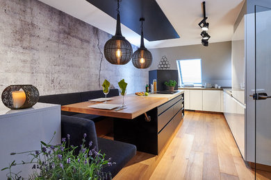 Geräumige Moderne Küche in L-Form mit flächenbündigen Schrankfronten, Betonarbeitsplatte, Kücheninsel, grauer Arbeitsplatte, weißen Schränken und hellem Holzboden in München