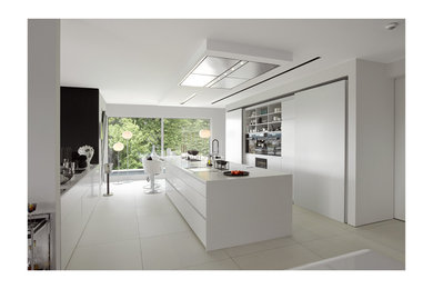 ドレスデンにあるラグジュアリーな巨大なコンテンポラリースタイルのおしゃれなキッチン (フラットパネル扉のキャビネット、白いキャビネット、人工大理石カウンター、白いキッチンパネル、磁器タイルの床) の写真