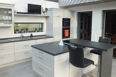 Foto de cocina de estilo de casa de campo abierta con puertas de armario grises y una isla