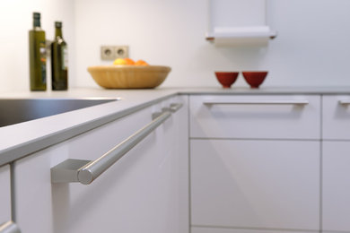 Geschlossene Moderne Küche ohne Insel in U-Form mit weißen Schränken, Küchenrückwand in Weiß und schwarzen Elektrogeräten in Bremen
