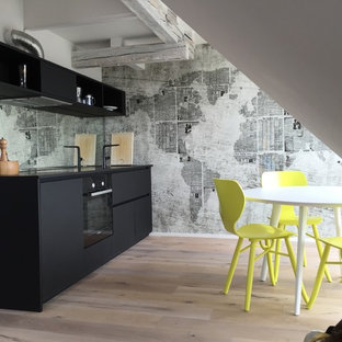 Ispirazione per una cucina industriale di medie dimensioni con ante lisce, ante nere, paraspruzzi a specchio, parquet chiaro, nessuna isola, elettrodomestici neri, top in quarzo composito, lavello integrato, paraspruzzi multicolore e pavimento marrone