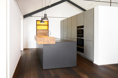 Moderne Küche mit flächenbündigen Schrankfronten, grauen Schränken, Quarzwerkstein-Arbeitsplatte und Kücheninsel in München