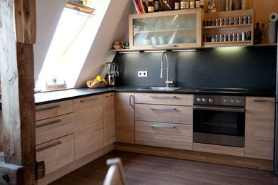 Moderne Küche in L-Form mit hellbraunen Holzschränken und Granit-Arbeitsplatte in Berlin