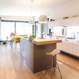 Zweizeilige, Mittelgroße Moderne Wohnküche mit Kücheninsel, flächenbündigen Schrankfronten, Küchenrückwand in Weiß, hellem Holzboden und beigem Boden in Frankfurt am Main