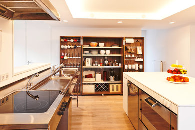 Esempio di un cucina con isola centrale nordico di medie dimensioni con lavello integrato, ante lisce, ante bianche, pavimento in legno massello medio e elettrodomestici in acciaio inossidabile