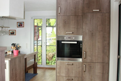 シュトゥットガルトにある広いコンテンポラリースタイルのおしゃれなキッチン (ダブルシンク、白いキャビネット、ラミネートカウンター、シルバーの調理設備) の写真