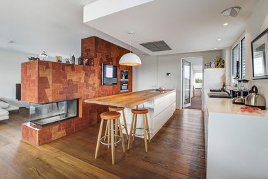 Offene Moderne Küche mit weißen Schränken, braunem Holzboden und Kücheninsel in Köln