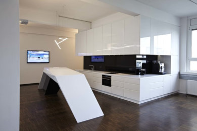 Moderne Küche mit Waschbecken, Glasfronten, weißen Schränken, Küchenrückwand in Schwarz, Glasrückwand, schwarzen Elektrogeräten und dunklem Holzboden in München