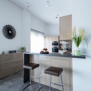 Offene, Kleine Moderne Küche in L-Form mit flächenbündigen Schrankfronten, braunen Schränken, schwarzen Elektrogeräten, Halbinsel, grauem Boden und schwarzer Arbeitsplatte in Nürnberg