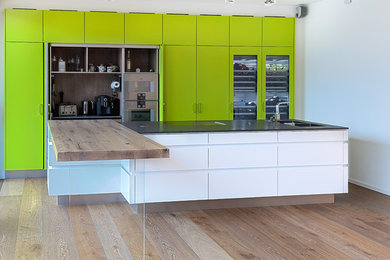 Offene Moderne Küche mit Doppelwaschbecken, grünen Schränken, Küchenrückwand in Braun, Küchengeräten aus Edelstahl und Kücheninsel in Köln