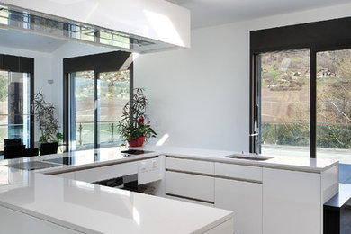 Ejemplo de cocinas en U contemporáneo abierto con fregadero integrado, armarios con paneles lisos, puertas de armario blancas, península, suelo gris y encimeras blancas
