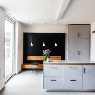 Immagine di una cucina scandinava chiusa e di medie dimensioni con ante lisce, ante grigie, top in legno, pavimento in gres porcellanato, penisola e elettrodomestici in acciaio inossidabile