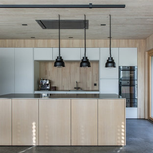 Zweizeilige Moderne Küche mit flächenbündigen Schrankfronten, weißen Schränken, Küchenrückwand in Beige, Rückwand aus Holz, Küchengeräten aus Edelstahl, Betonboden, Kücheninsel, grauem Boden und grauer Arbeitsplatte in Sonstige