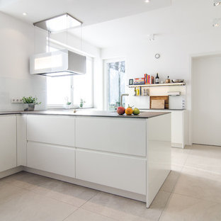 Geschlossene, Mittelgroße Moderne Küche in L-Form mit flächenbündigen Schrankfronten, weißen Schränken, Küchenrückwand in Weiß, Glasrückwand, schwarzen Elektrogeräten, Halbinsel und beigem Boden in Frankfurt am Main