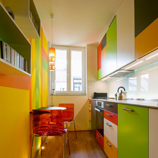 Kleine, Geschlossene, Einzeilige Moderne Küche ohne Insel mit flächenbündigen Schrankfronten, Küchenrückwand in Weiß, Glasrückwand, schwarzen Elektrogeräten, braunem Holzboden und braunem Boden in München