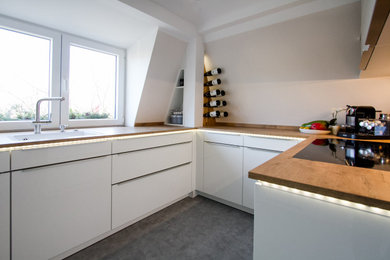 Exempel på ett modernt kök, med vita skåp och träbänkskiva