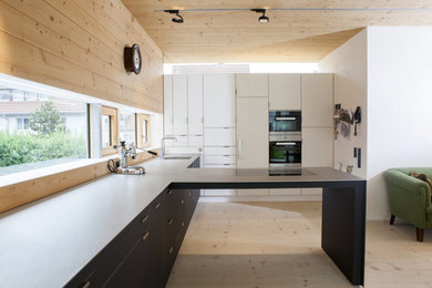 Imagen de cocinas en L contemporánea abierta con puertas de armario blancas y electrodomésticos de acero inoxidable