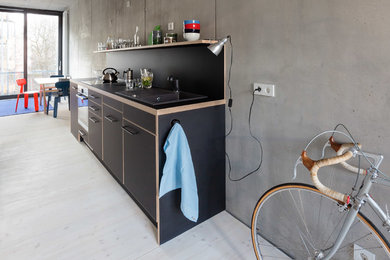 Exemple d'une petite cuisine ouverte industrielle avec des portes de placard noires.