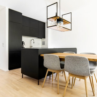 Offene, Zweizeilige, Mittelgroße Moderne Küche mit flächenbündigen Schrankfronten, schwarzen Schränken, hellem Holzboden, Kücheninsel und beigem Boden in München