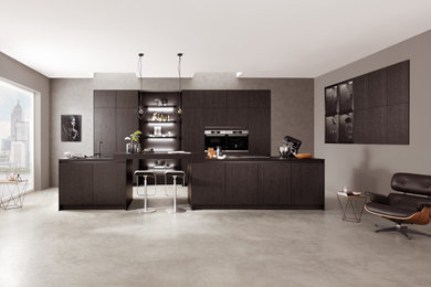 Offene Moderne Küche mit dunklen Holzschränken, Kücheninsel und schwarzer Arbeitsplatte in Sonstige