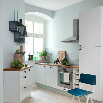 Kitchen - small contemporary light wood floor kitchen idea in Berlin with an undermount sink, flat-panel cabinets, wood countertops, glass sheet backsplash, no island, white cabinets, blue backsplash and stainless steel appliances