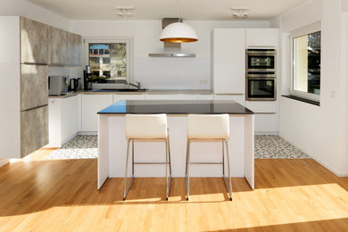 Moderne Wohnküche in L-Form mit Küchengeräten aus Edelstahl und Kücheninsel in Sonstige
