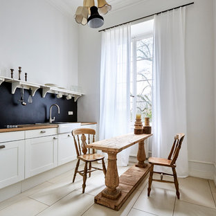 Offene, Einzeilige, Kleine Klassische Küche ohne Insel mit integriertem Waschbecken, Kassettenfronten, weißen Schränken, Arbeitsplatte aus Holz, Küchenrückwand in Schwarz, Porzellan-Bodenfliesen und beigem Boden in Frankfurt am Main