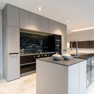 Offene, Zweizeilige, Große Moderne Küche mit Einbauwaschbecken, flächenbündigen Schrankfronten, grauen Schränken, Mineralwerkstoff-Arbeitsplatte, Küchenrückwand in Grau, schwarzen Elektrogeräten, Marmorboden, Kücheninsel, beigem Boden und schwarzer Arbeitsplatte in Köln