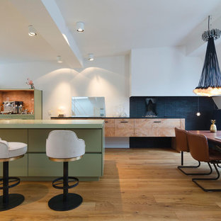 Zweizeilige Moderne Wohnküche mit flächenbündigen Schrankfronten, grünen Schränken, braunem Holzboden, Kücheninsel, braunem Boden und grüner Arbeitsplatte in Hamburg