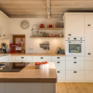 Kleine Landhaus Wohnküche mit Landhausspüle, weißen Schränken, Arbeitsplatte aus Holz, weißen Elektrogeräten, braunem Holzboden, Halbinsel, braunem Boden, brauner Arbeitsplatte und flächenbündigen Schrankfronten in München