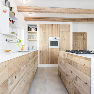 Inspiration for a large industrial galley open plan kitchen in Munich with an undermount sink, flat-panel cabinets, light wood cabinets, solid surface benchtops, concrete floors and with island.