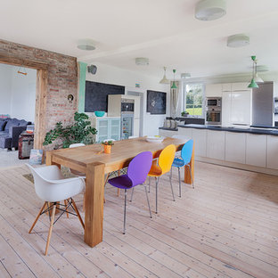Modelo de cocina comedor en L, contemporánea, grande, con fregadero sobremueble, armarios con paneles lisos, puertas de armario beige, electrodomésticos de acero inoxidable, suelo de madera clara y península